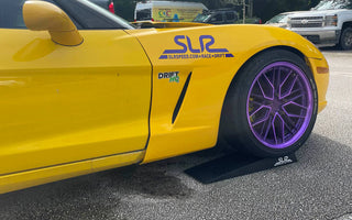 Low profile car ramp under a slammed vehicle with oil drain pan ready beneath.