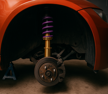 A lowered sports car showing off adjustable coilovers in a garage setup, wheels off, suspension visible.