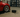 A low-profile sports car on SLR split race ramps in a garage, with jack and tools nearby